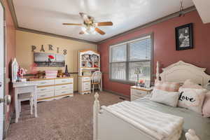 Carpeted bedroom featuring baseboards, crown molding, and ceiling fan