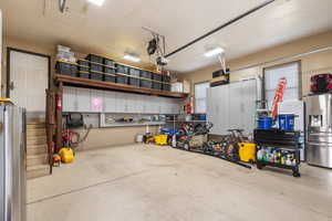 Garage featuring freestanding refrigerator, stainless steel fridge with ice dispenser, and a garage door opener