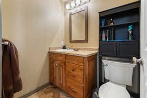 Half bathroom with baseboards, toilet, and vanity
