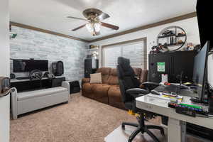 Office area with carpet flooring, a ceiling fan, crown molding, and an accent wall
