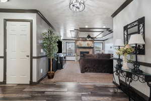 Living room featuring a brick fireplace, baseboards, ornamental molding, wood finished floors, and ceiling fan