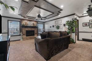 Living area with carpet flooring, a ceiling fan, ornamental molding, and a textured ceiling