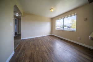 Unfurnished room featuring baseboards, visible vents, and dark wood-type flooring