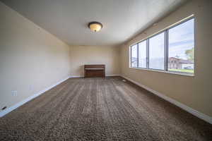 Carpeted empty room featuring baseboards and a textured ceiling