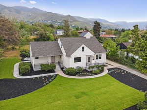 View of front facade with a front yard, roof with shingles, and a mountain view