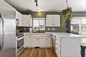Kitchen with white cabinets, a peninsula, a sink, and appliances with stainless steel finishes