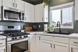 Kitchen featuring white cabinets, a sink, stainless steel appliances, and light countertops
