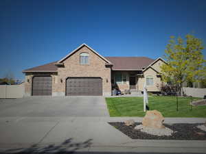 View of front of property featuring fence, a front lawn, brick siding, and concrete driveway