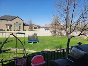 View of yard with a trampoline, a residential view, and a fenced backyard