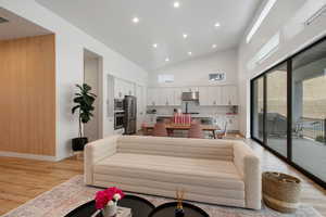 Living area featuring recessed lighting, baseboards, light wood-type flooring, and a towering ceiling