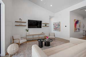 Living room featuring vaulted ceiling, recessed lighting, wood finished floors, and baseboards