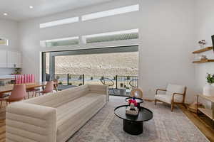 Living room featuring recessed lighting, baseboards, a high ceiling, and wood finished floors