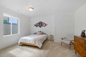 Bedroom with light carpet, visible vents, and baseboards