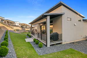 Rear view of house with a lawn, fence, and stucco siding