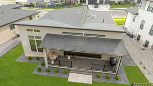 Back of property with stucco siding, a lawn, a residential view, and a shingled roof