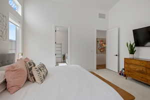 Bedroom featuring baseboards, visible vents, a towering ceiling, and carpet floors