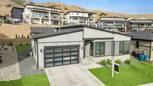 Modern home featuring concrete driveway, central air condition unit, a mountain view, and a residential view