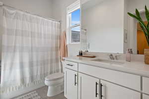 Full bath with toilet, shower / tub combo with curtain, vanity, and tile patterned flooring