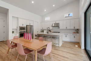 Kitchen featuring light wood-type flooring, under cabinet range hood, a sink, stainless steel appliances, and light countertops