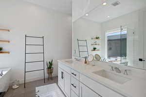 Full bathroom with tile patterned flooring, visible vents, a freestanding bath, and a sink