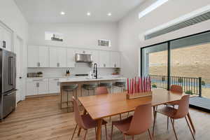 Dining space with light wood finished floors, visible vents, recessed lighting, and high vaulted ceiling