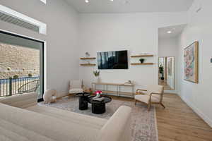 Living room featuring recessed lighting, a high ceiling, baseboards, and wood finished floors