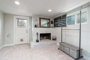 Carpeted family room featuring a high end fireplace, baseboards, and recessed lighting