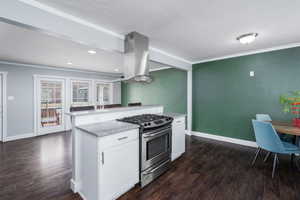 Kitchen featuring white cabinetry, ornamental molding, island exhaust hood, stainless steel gas range, and dark wood-style floors