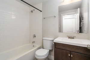 Full bathroom featuring bathtub / shower combination, toilet, vanity, a textured ceiling, and baseboards