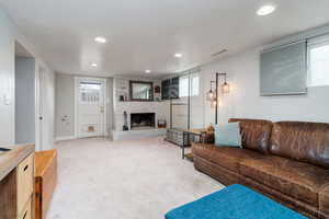 Carpeted family room featuring visible vents, baseboards, a fireplace, and recessed lighting