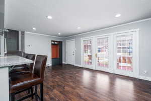 Living room with baseboards, dark wood-style floors, recessed lighting, and ornamental molding