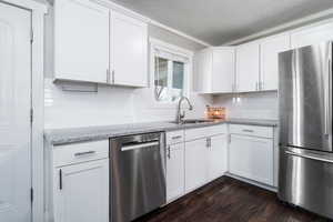 Kitchen with a sink, white cabinetry, appliances with stainless steel finishes, and dark wood-style flooring