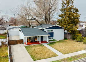 View of front of property featuring a front yard, covered porch, roof with shingles, fence, and brick siding