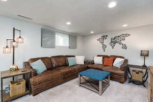 Carpeted family room featuring a textured ceiling, visible vents, and recessed lighting