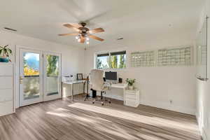 Office area with baseboards, visible vents, wood finished floors, and ceiling fan