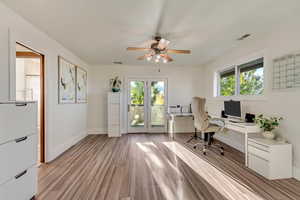 Office area with light wood-type flooring, visible vents, baseboards, and ceiling fan