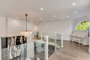Hall with a notable chandelier, wood finished floors, an upstairs landing, and recessed lighting