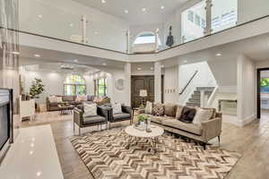 Living room featuring stairway, recessed lighting, a towering ceiling, arched walkways, and light wood-style floors