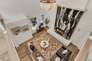 Interior space with baseboards, wood finished floors, a chandelier, and a glass covered fireplace
