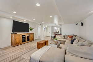 Living room with light wood-style floors, baseboards, and recessed lighting