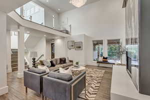 Living area with stairway, wood finished floors, baseboards, a towering ceiling, and recessed lighting