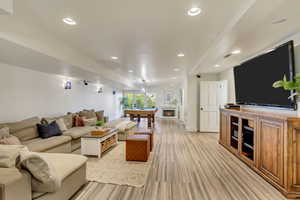 Living area featuring a warm lit fireplace, visible vents, recessed lighting, and light wood-style floors