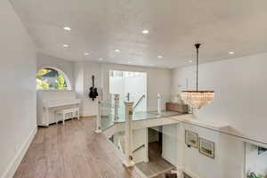 Office space with recessed lighting, a notable chandelier, baseboards, and light wood-type flooring