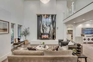 Living area featuring baseboards, a high ceiling, wood finished floors, and a multi sided fireplace