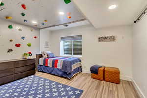 Bedroom featuring baseboards, a barn door, wood finished floors, and recessed lighting