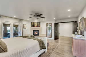 Bedroom featuring light wood finished floors, access to outside, recessed lighting, a glass covered fireplace, and french doors