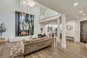 Living area with arched walkways, a multi sided fireplace, recessed lighting, and light wood-style floors
