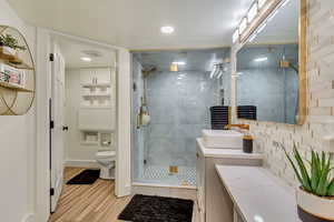 Bathroom featuring a stall shower, toilet, vanity, wood finished floors, and visible vents