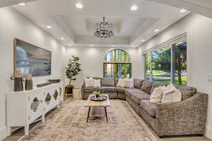 Living area with a tray ceiling, recessed lighting, and a chandelier