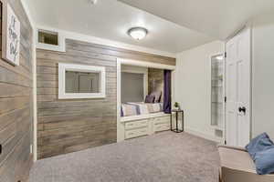 Interior space featuring wooden walls, carpet floors, and a textured ceiling